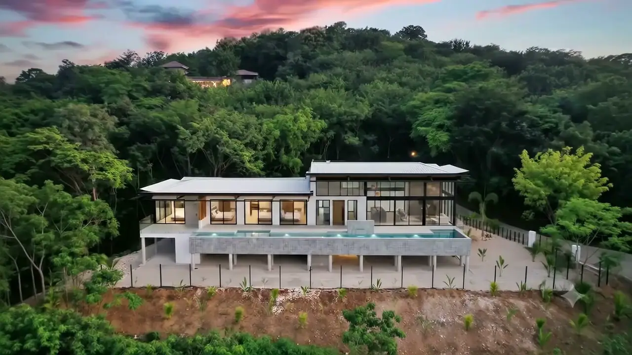 Vista aérea de una casa moderna con piscina rodeada de bosque tropical